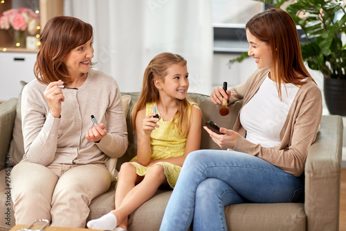 family, generation and female concept - portrait of smiling mother, daughter and grandmother with cosmetics doing make up at home