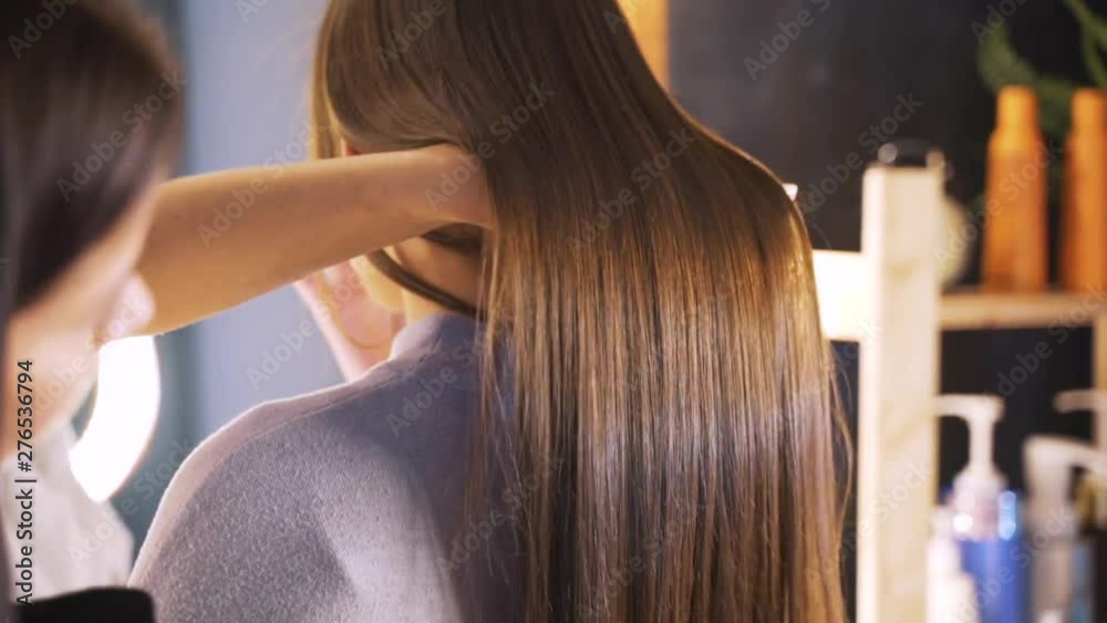 Long dark hair of a young girl. Brilliant and silky hair after keratin straightening. The effect of keratin, botox, straight hair. The concept of beauty salons, beauty.