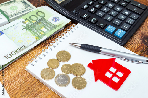 Red home house notepad pen on the banknotes and coins background euro pile pack real estate concept expenses property buying mockup copy space close up background selective focus