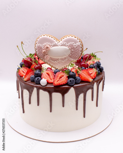 Wedding cake with chocolate drops decorated with gingerbread, berries and macaroons. On a white background.