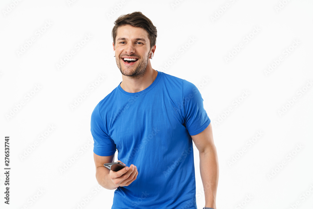Photo closeup of caucasian man in casual t-shirt smiling and holding smartphone while wearing wireless earpods