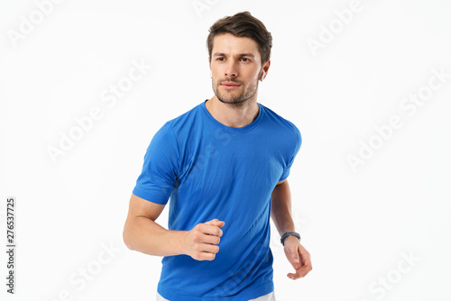 Photo closeup of handsome man in casual t-shirt smiling and running while wearing wireless earpods