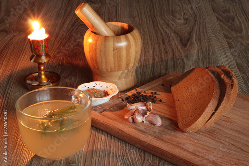 still life with broth seasoning and candle on a wooden background