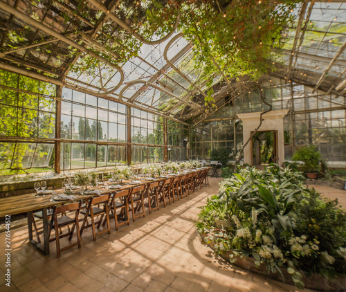 Huge greenhouse for exotic plants rented for the wedding ceremony decorated in the Art Nouveau style