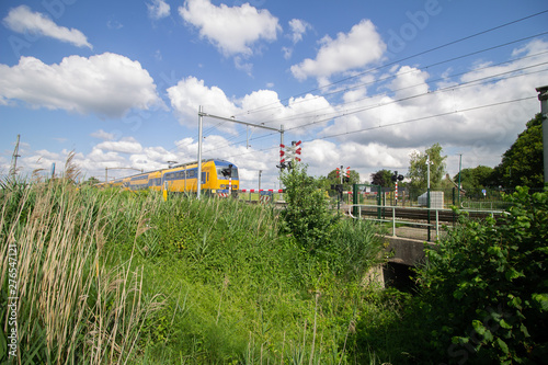 Obraz na plátně Train heading towards a level crossing on a sunny day