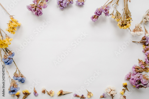 Fototapeta Naklejka Na Ścianę i Meble -  Frame made of dried colored flowers on a white background. copy space. Romantic flowers. Place for text and design. Greeting card. Flat lay, top view. Flowers composition.