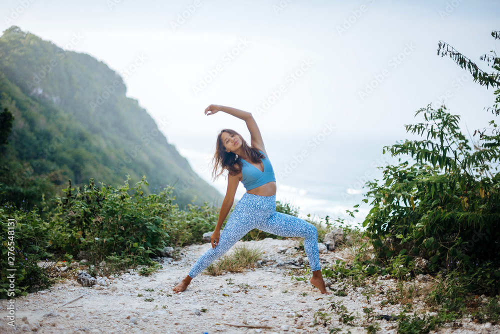 Girl practice yoga near ocean.