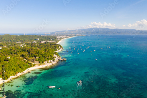 Tourist boats off the coast of the island of Boracay, Philippines, aerial view. Big island with hotels and a white beach. Seascape with a beautiful coast.