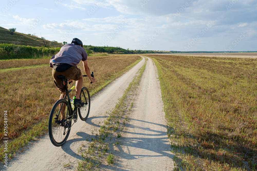 Cyclist bicycle biker in safety helmet ride high speed landscape from behind Cyclist bicycle biker in safety helmet ride high speed landscape from behind