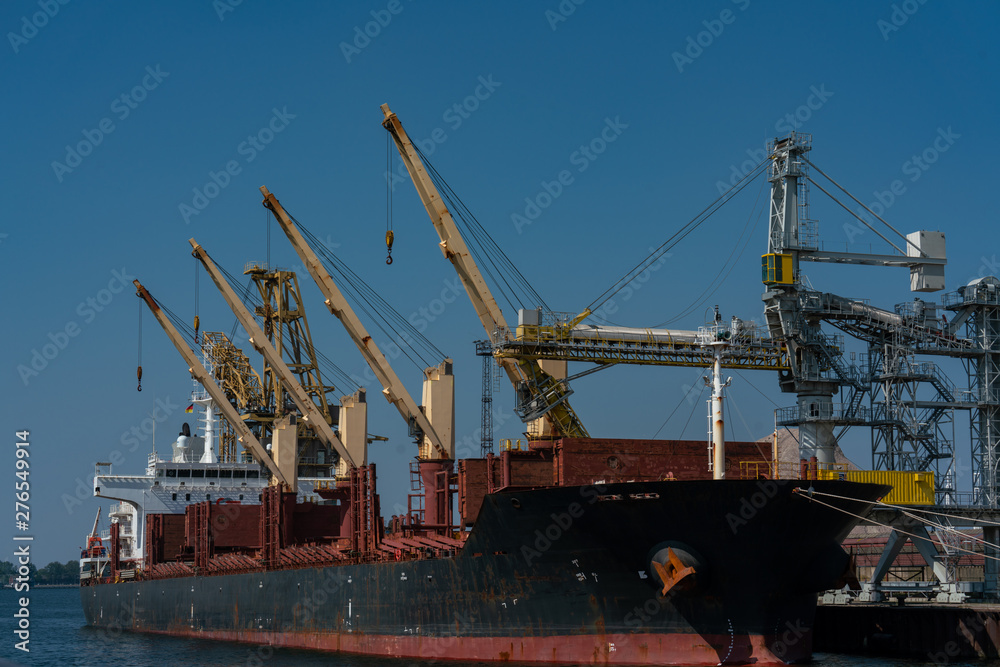 yellow dockside cranes and a black ship at the industrial harbour in Rostock