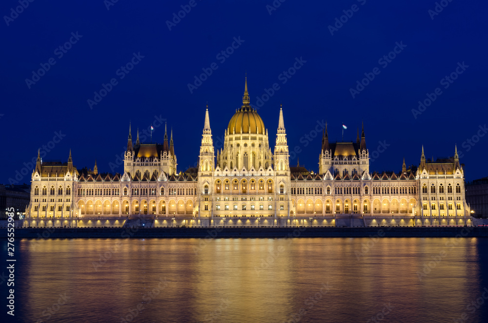 Illuminated Budapest hungarian Parliament at night reflected in the Danube river.