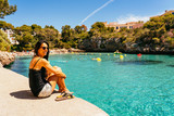 Woman enjoying the view of turquoise water in Cala Ferrera in a sunny day, Cala D'Or, Majorca.