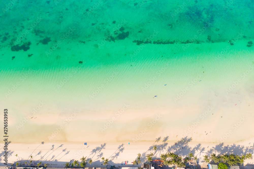 Tropical beach with white sand and palm trees, view from above. Turquoise lagoon with a sandy bottom. Beach of the island of Boracay, Philippines.