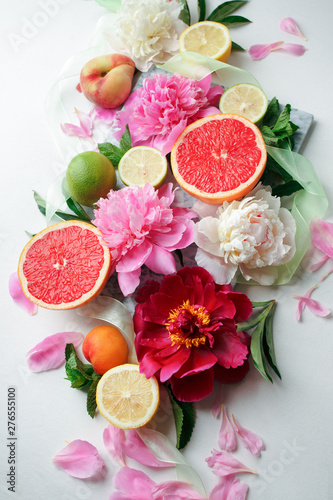Still life with fresh assorted exotic fruits and peony flowers on white background. Concept of healthy eating with fruits and seasonal flowers. Wedding decor