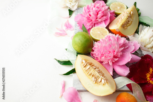 Fototapeta Naklejka Na Ścianę i Meble -  Still life with fresh assorted exotic fruits and peony flowers on white background. Concept of healthy eating with fruits and seasonal flowers. Wedding decor