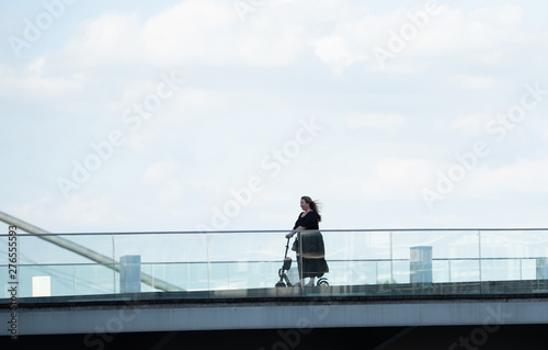 side view of an obese business woman riding an electric scooter driving over a bridge at media harbor Duesseldorf