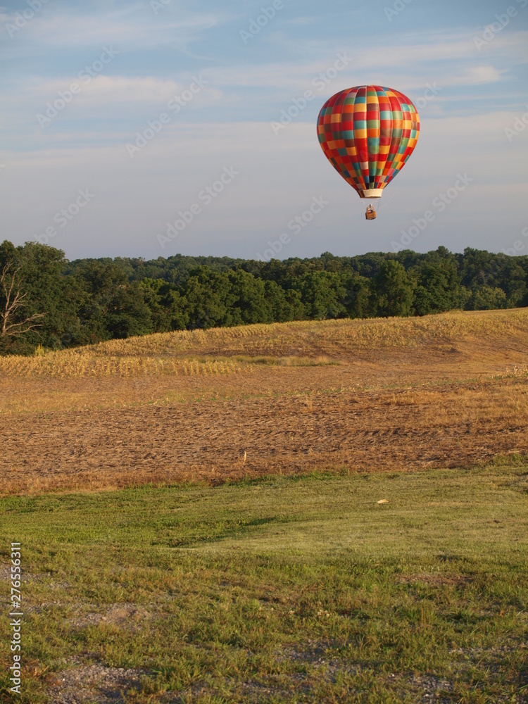 Obraz premium Hot air balloon hovers over farm fields