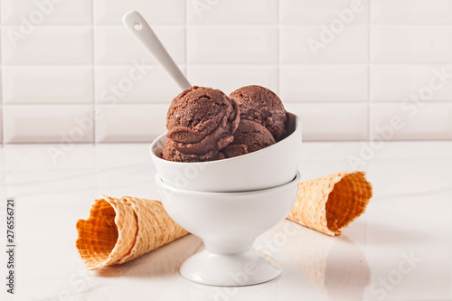 Chocolate ice cream bowl and cones on the white surface.