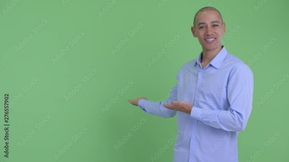 Happy bald multi ethnic businessman talking while showing to back Happy bald multi ethnic businessman talking while showing to back