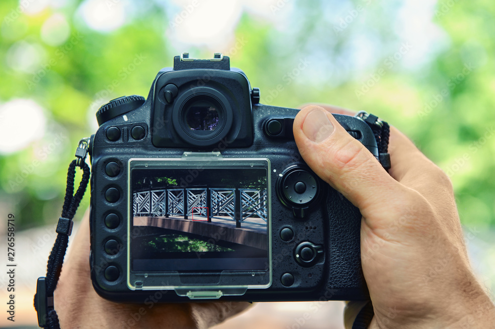 A photographer is photographing the bridge. He is holding the camera. A photographer is photographing the bridge. He is holding the camera.
