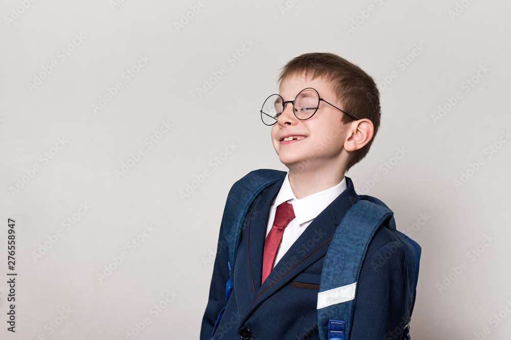 Portrait of a curious schoolboy in a suit, glasses and a backpack. School concept. White background. Portrait of a curious schoolboy in a suit, glasses and a backpack. School concept. White background.