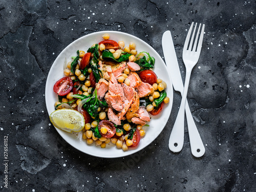 Warm chickpeas, cherry tomatoes, spinach, roasted salmon salad  - healthy lunch on a dark background, top view
