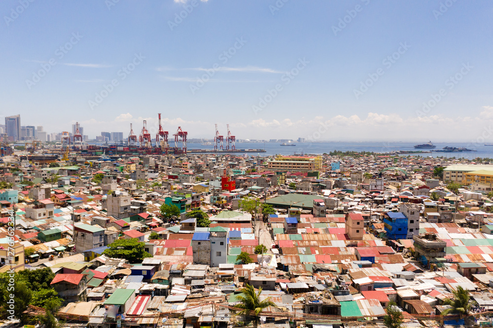 Port in Manila, Philippines. Sea port with cargo cranes. Cityscape with poor areas and business center in the distance, view from above. Asian metropolis.