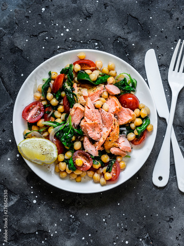 Warm chickpeas, cherry tomatoes, spinach, roasted salmon salad - healthy lunch on a dark background, top view