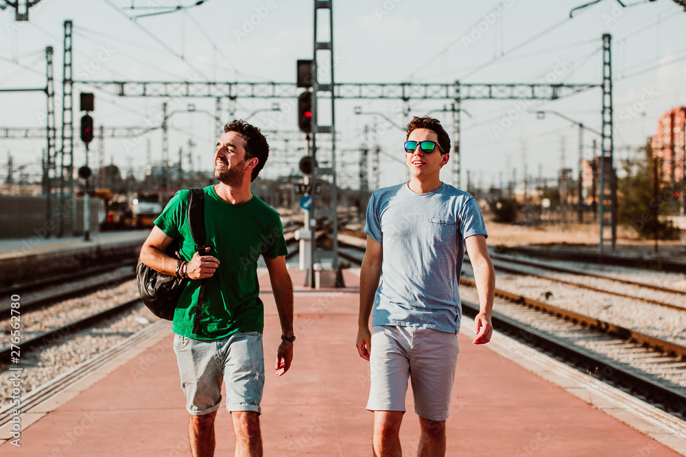 .Two brothers on the platform waiting for the train. Relaxed and fun to start their vacation. Lifestyle. Travel photography