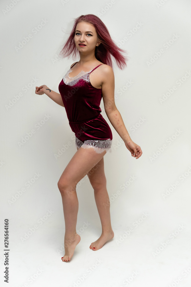 Concept portrait of a full-length pretty sexy girl with purple hair in beautiful red lingerie on a white background. She smiles, happy with life, happy. Hair flying, front view. Made in a studio. Concept portrait of a full-length pretty sexy girl with purple hair in beautiful red lingerie on a white background. She smiles, happy with life, happy. Hair flying, front view. Made in a studio.