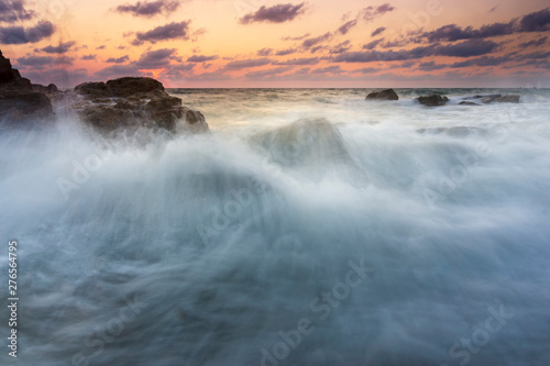 Beautiful natural seascape wave hit the rock during sunset