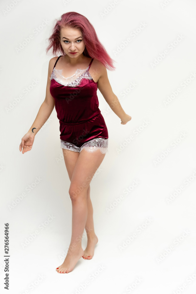 Concept portrait of a full-length pretty sexy girl with purple hair in beautiful red lingerie on a white background. She smiles, happy with life, happy. Hair flying, front view. Made in a studio. Concept portrait of a full-length pretty sexy girl with purple hair in beautiful red lingerie on a white background. She smiles, happy with life, happy. Hair flying, front view. Made in a studio.