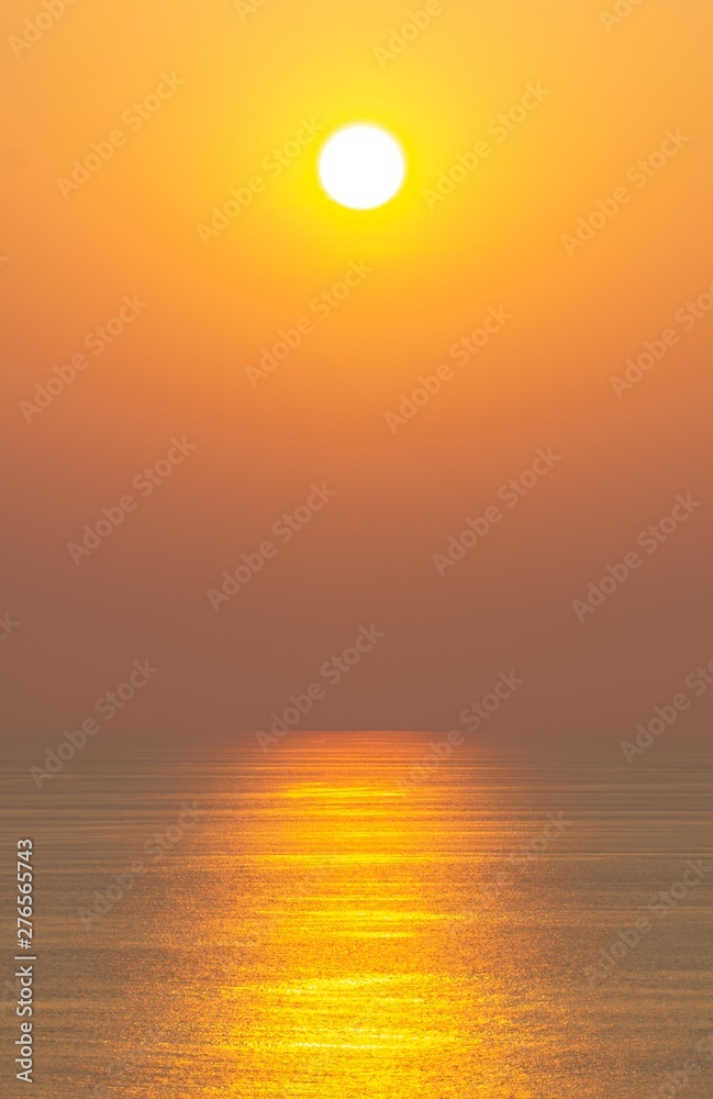 The sunset, the sea surface reflects the sunlight in gold. Clear sky, orange without clouds