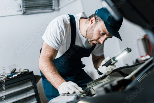 selective focus of bearded car mechanic holding flashlight near car © LIGHTFIELD STUDIOS