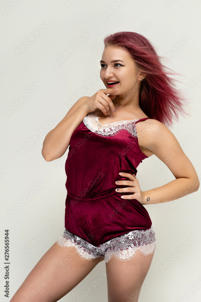 Concept portrait of a knee-high pretty sexy girl with purple hair in beautiful red lingerie on a white background. She smiles, happy with life, happy. Hair flying, front view. Made in a studio. Concept portrait of a knee-high pretty sexy girl with purple hair in beautiful red lingerie on a white background. She smiles, happy with life, happy. Hair flying, front view. Made in a studio.