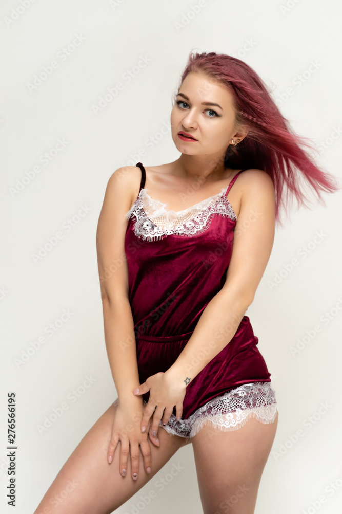 Concept portrait of a knee-high pretty sexy girl with purple hair in beautiful red lingerie on a white background. She smiles, happy with life, happy. Hair flying, front view. Made in a studio. Concept portrait of a knee-high pretty sexy girl with purple hair in beautiful red lingerie on a white background. She smiles, happy with life, happy. Hair flying, front view. Made in a studio.