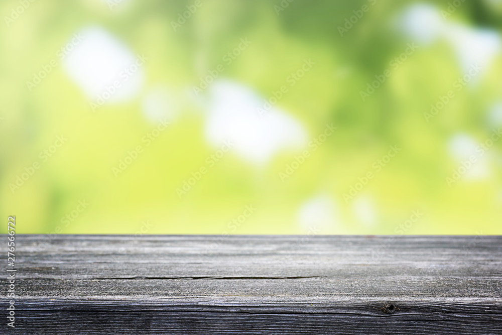 Fototapeta premium Blurred abstract green yellow bokeh and wooden table background.