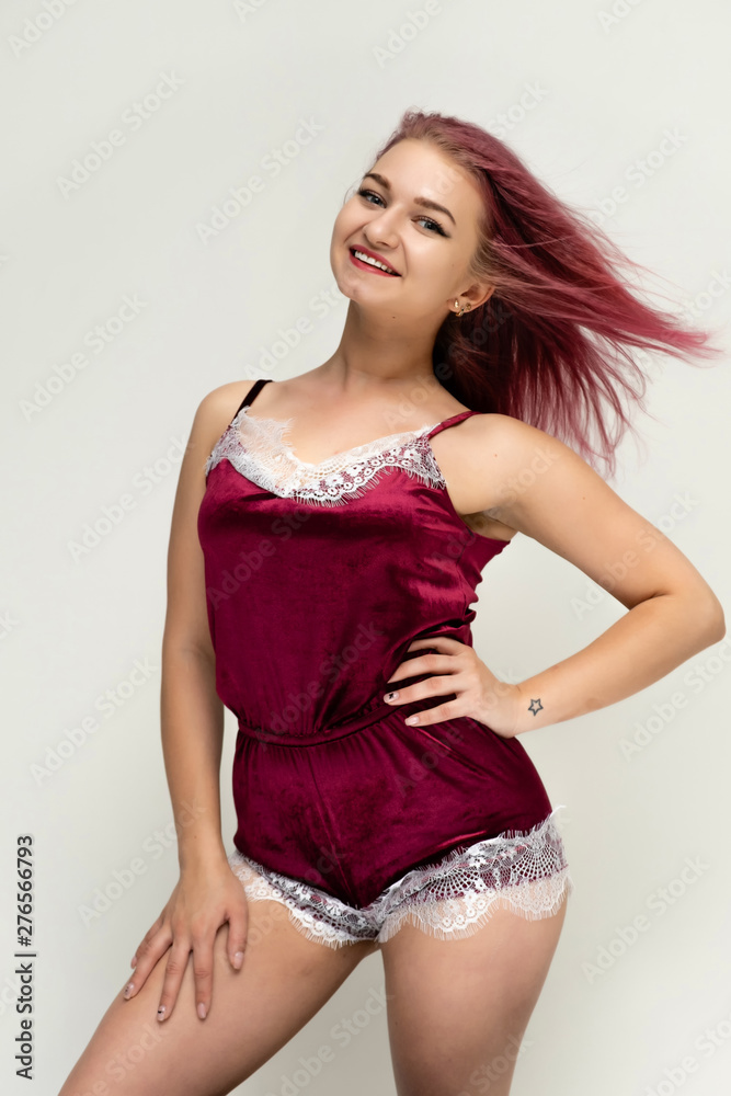 Concept portrait of a knee-high pretty sexy girl with purple hair in beautiful red lingerie on a white background. She smiles, happy with life, happy. Hair flying, front view. Made in a studio. Concept portrait of a knee-high pretty sexy girl with purple hair in beautiful red lingerie on a white background. She smiles, happy with life, happy. Hair flying, front view. Made in a studio.