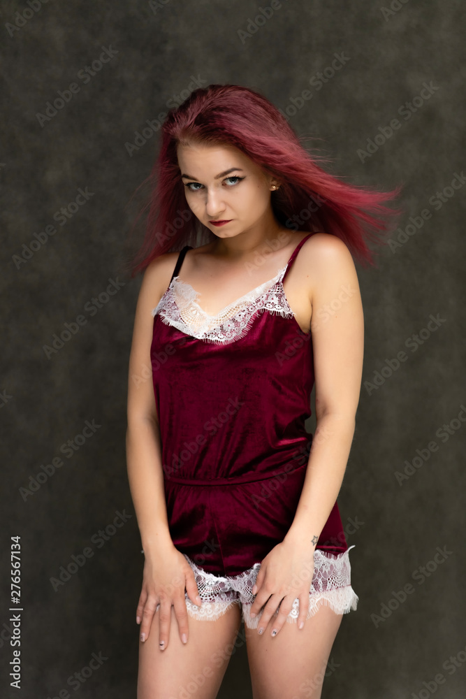 Concept portrait of a knee-high pretty sexy girl with purple hair in beautiful red lingerie on a gray background. She smiles, happy with life, happy. Hair flying, front view. Made in a studio. Concept portrait of a knee-high pretty sexy girl with purple hair in beautiful red lingerie on a gray background. She smiles, happy with life, happy. Hair flying, front view. Made in a studio.