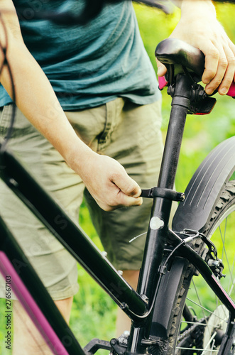A man straightens, repairs the seat of a mountain bike on a forest road. Bicycle breakdown, vehicle repair.