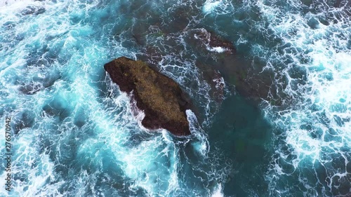 Drone, aerial or top view moving up away ocean blue waves crash coastline cliff drone footage. Dangerous place for moored ships. The water is like marble and crystal clear salt water. Waves break on