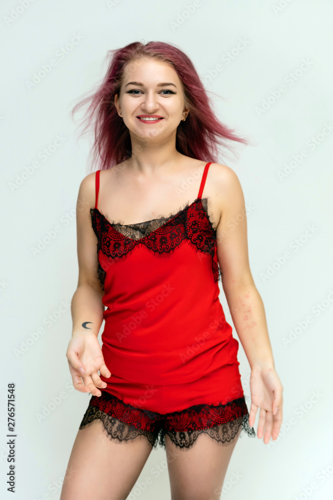 Concept portrait of a pretty sexy girl with purple hair in beautiful red lingerie on a white background. She smiles, happy with life, happy. Hair flying, front view. Made in a studio. Concept portrait of a pretty sexy girl with purple hair in beautiful red lingerie on a white background. She smiles, happy with life, happy. Hair flying, front view. Made in a studio.