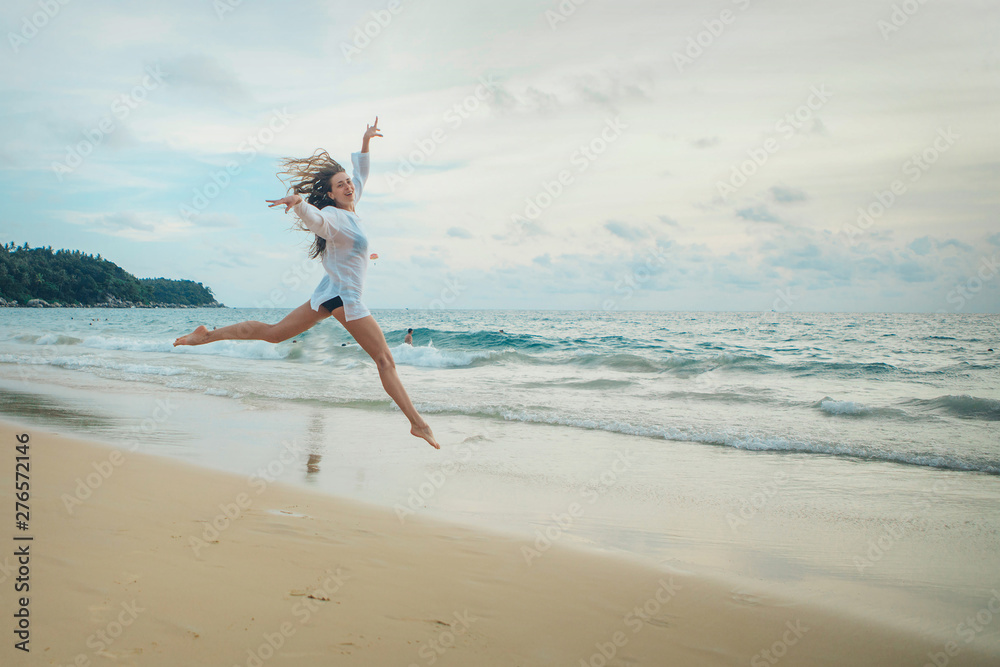 woman jumping happy in the beach with a blue sky and sea in the background