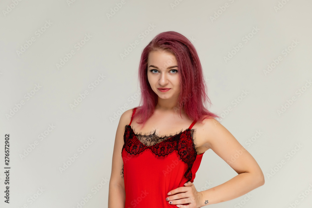 Concept portrait of a pretty sexy girl with purple hair in beautiful red lingerie on a white background. She smiles, happy with life, happy. Hair flying, front view. Made in a studio. Concept portrait of a pretty sexy girl with purple hair in beautiful red lingerie on a white background. She smiles, happy with life, happy. Hair flying, front view. Made in a studio.