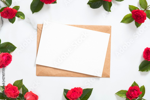 Mockup postcard with craft paper envelope and rose flowers frame on marble background. Minimal style composition, flat lay, view from above. Romantic love letter concept.
