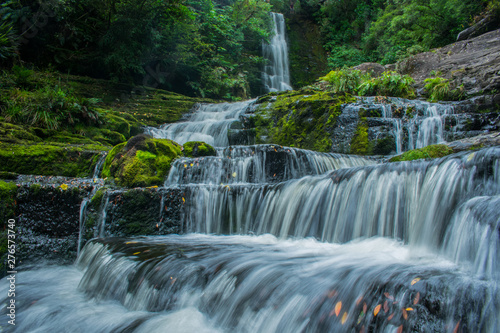 Una gran cascada al fondo y el agua corriendo en larga exposicion entre la naturaleza