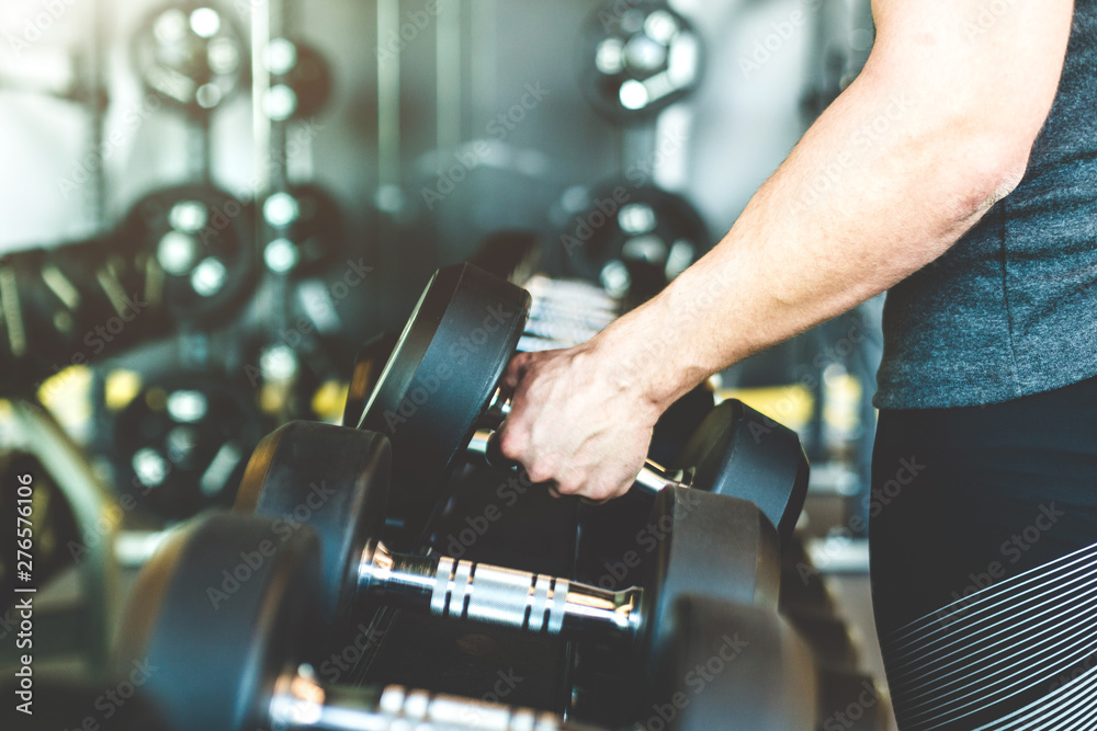Working out with dumbbell weights at the gym.Fitness men exercising are lifting dumbbells. Fitness muscular body. Workout at gym.