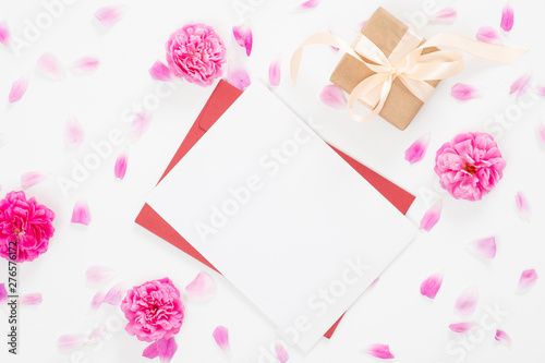 Top view blank paper card, red envelope, gift box, rose flowers buds and petals on white background. Minimal flat lay style composition, Love letter, greeting card concept. © photoguns