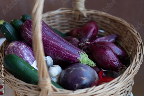 Wicker basket full of vegetables: aubergines, zucchini, onions and garlic