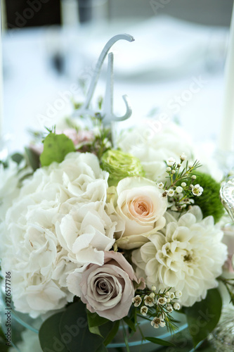 Wedding table setting is decorated with fresh flowers and white candles. Wedding floristry. Bouquet with roses  hydrangea and eustoma. Table numbering